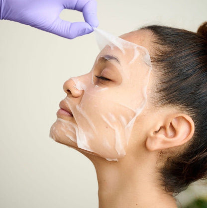 KrX Tranexamic Acid + Arbutin Home Care Mask being applied; a professional solution that solves the "mask-slippage" problem with an ultra-thin, second-skin Tencel material that adheres perfectly to facial contours, allowing for hands-free brightening without sliding or dripping.