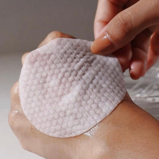 The soft, lint-free texture of a KrX Essence Cream Pad being applied to the skin, showing the immediate 'Korean glass skin' glow and intense moisture infusion without irritation