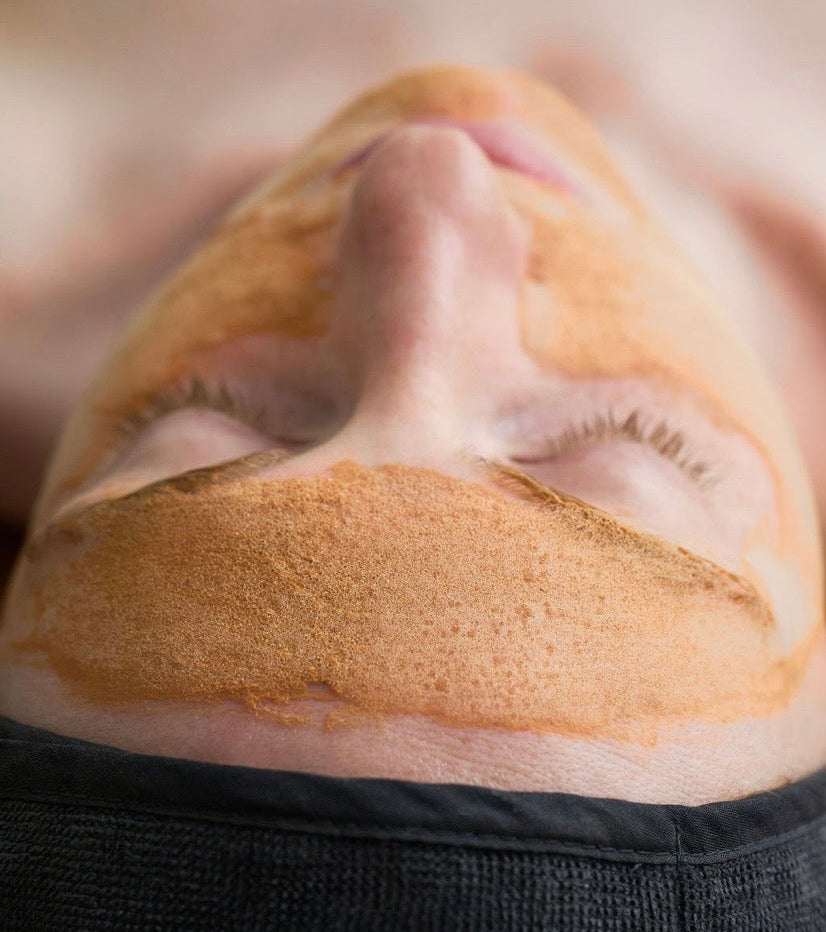 Close-up of KrX Aesthetics Pumpkin Enzyme Cleanser foaming on the skin to dissolve dead skin cells and purify pores during a professional K-beauty facial.