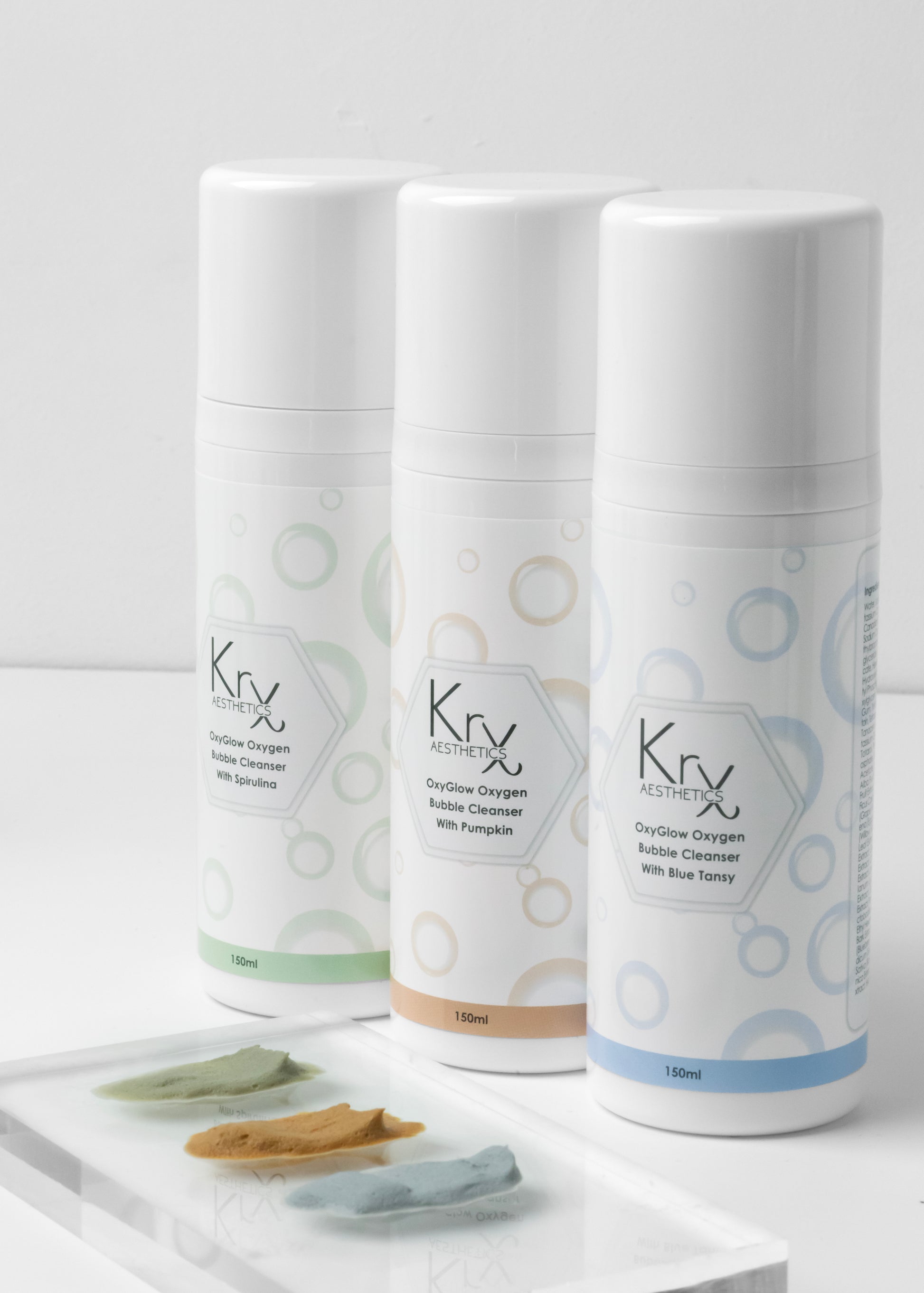 The KrX Aesthetics professional cleanser lineup featuring the OxyGlow Pumpkin Bubble Cleanser, Green Tea, and Blue Lotus formulas for a customized clinical skincare routine.