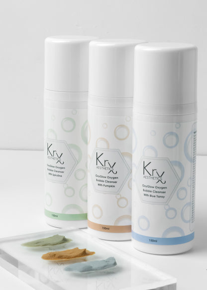 The KrX Aesthetics professional cleanser lineup featuring the OxyGlow Pumpkin Bubble Cleanser, Green Tea, and Blue Lotus formulas for a customized clinical skincare routine.