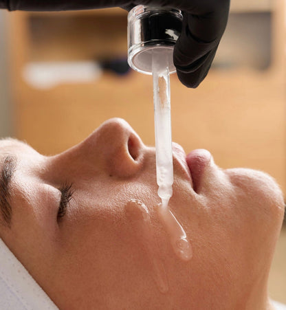 Applying liquid microneedling PDRN serum to skin with dropper during a Korean anti-aging spicule facial treatment.