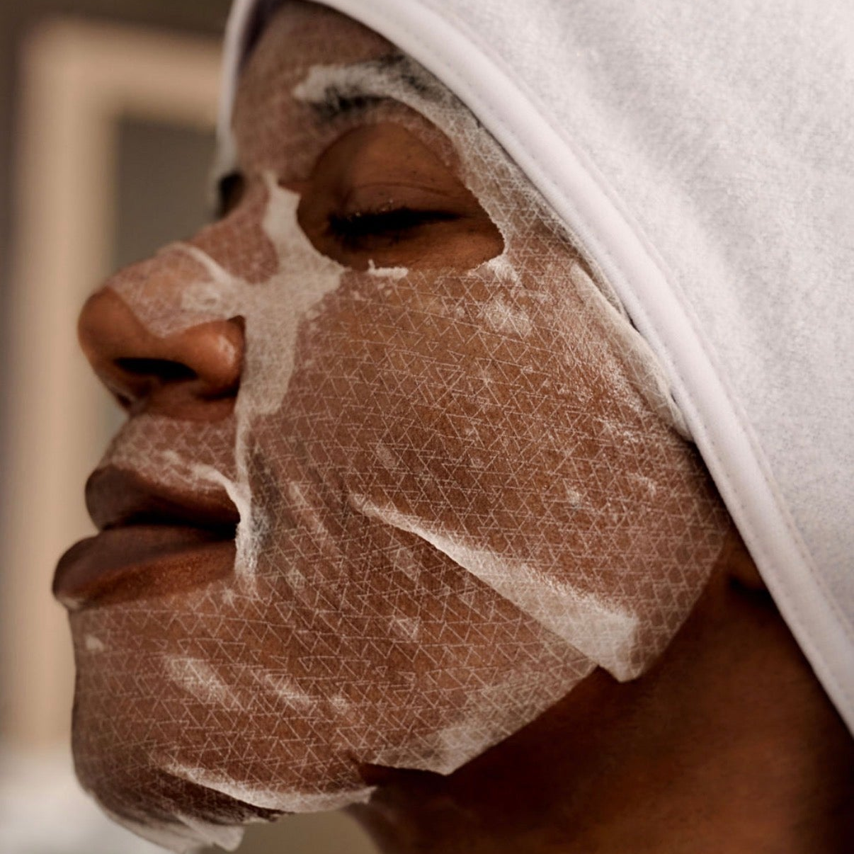 Applying the premium Korean Thesera Superbly Shape Holding Mask, showing the high-adhesion second-skin biocellulose material.